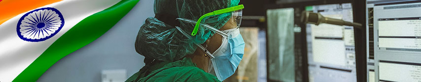 foto de primer plano de medico mujer con tapabocas de perfil viendo una pantalla de computador, al costado la bandera de India