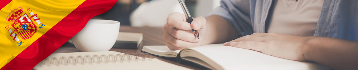 foto de manos de estudiante escribiendo notas en un cuaderno y bandera de España 