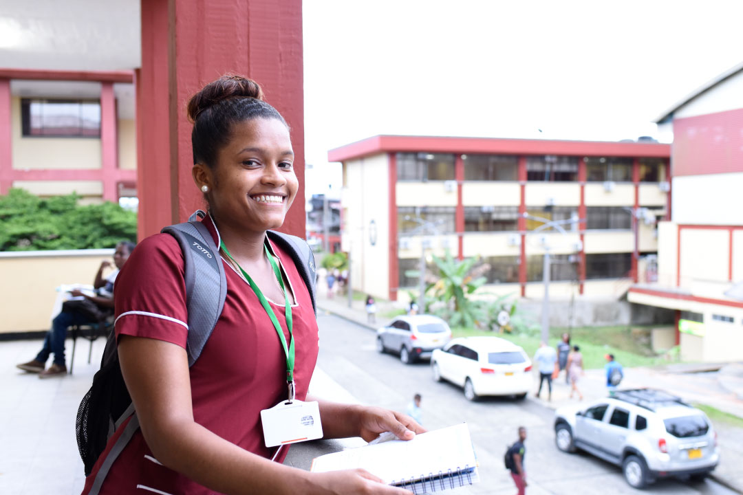 Fotografía de jóven estudiante afrodecendiente sonriendo y con uniforme de estudiante