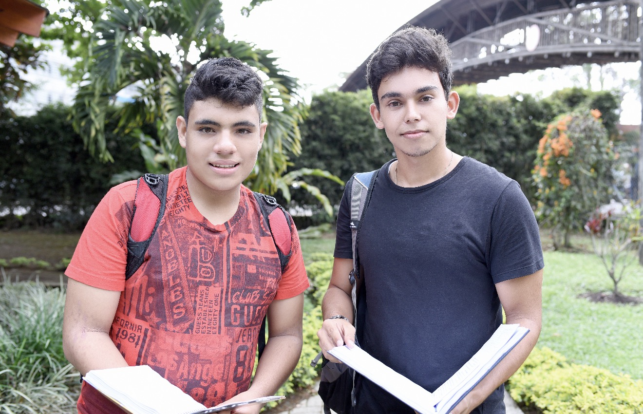 Imagen estudiantes con libro en mano sonriendo a la cámara 