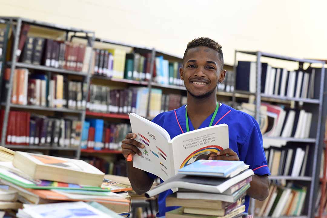 Imagen beneficiario de ICETEX leyendo libro en una biblioteca