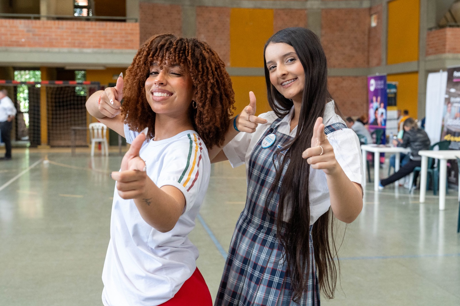 Imagen de dos estudiantes de colegio sonriendo y haciendo signo de aprobacion con los dedos