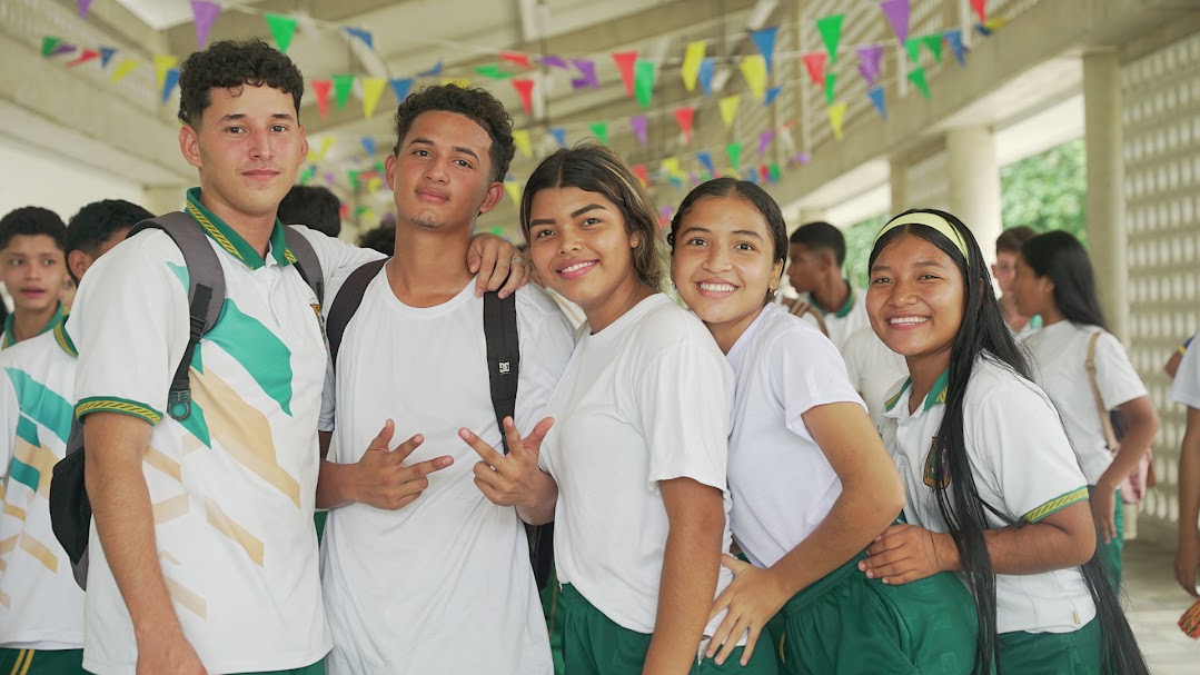 Imagen de 5 estudiantes de colegio en grupo abrazados sonriendo