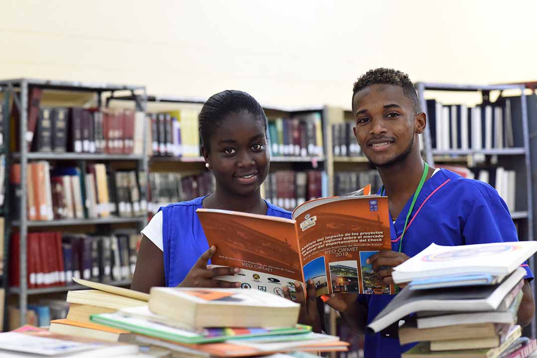 Estudiantes universitarios en la biblioteca leyendo libros felices