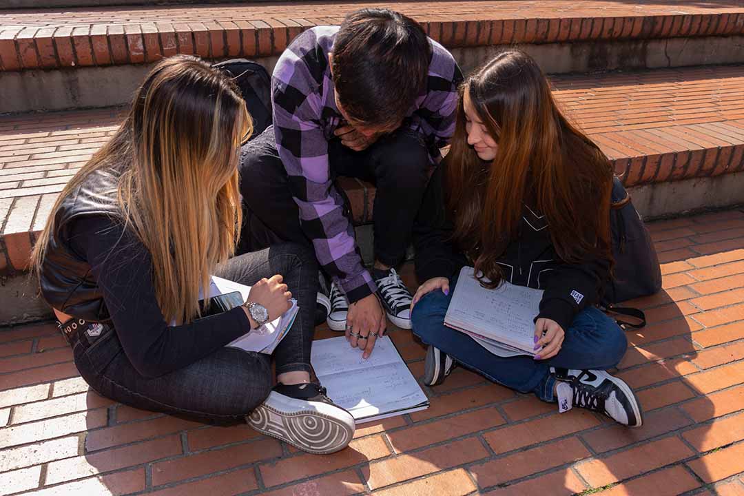 Imagen de cinco estudiantes sonriendo y abrazados asistiendo a un evento de ICETEX