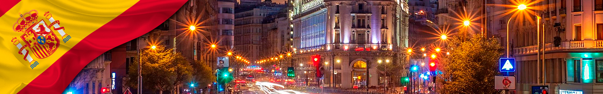 bandera de España ondeando con foto nocturna de la gran vía en Madrid